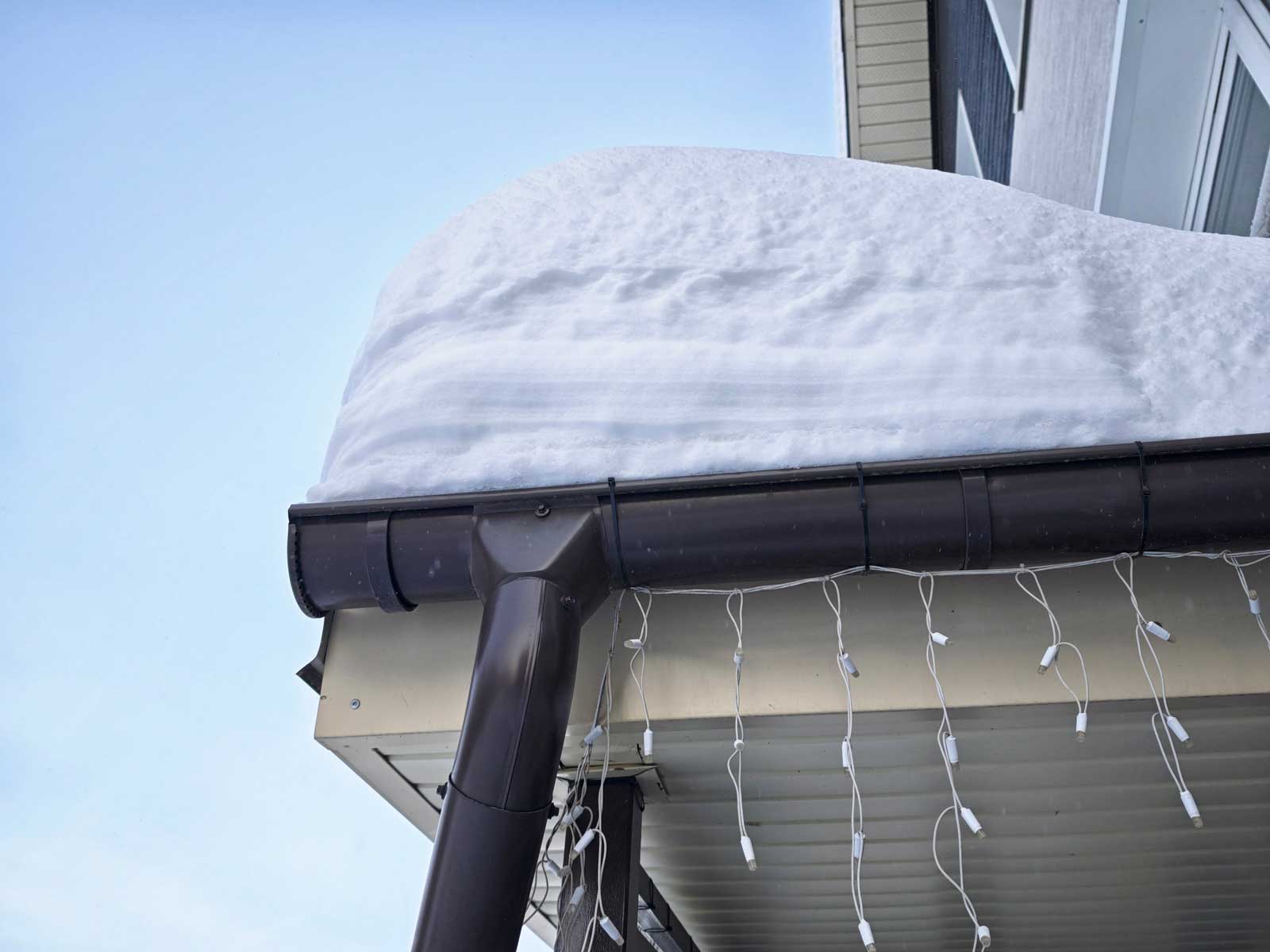 Winter snow covers a house roof showing the need for snow removal in a residential area during the cold season